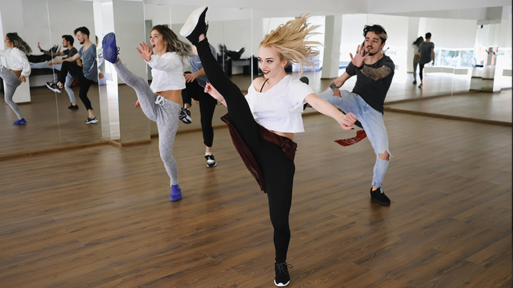 Turma de hip-hop em aula, com pontapé alto em primeiro plano